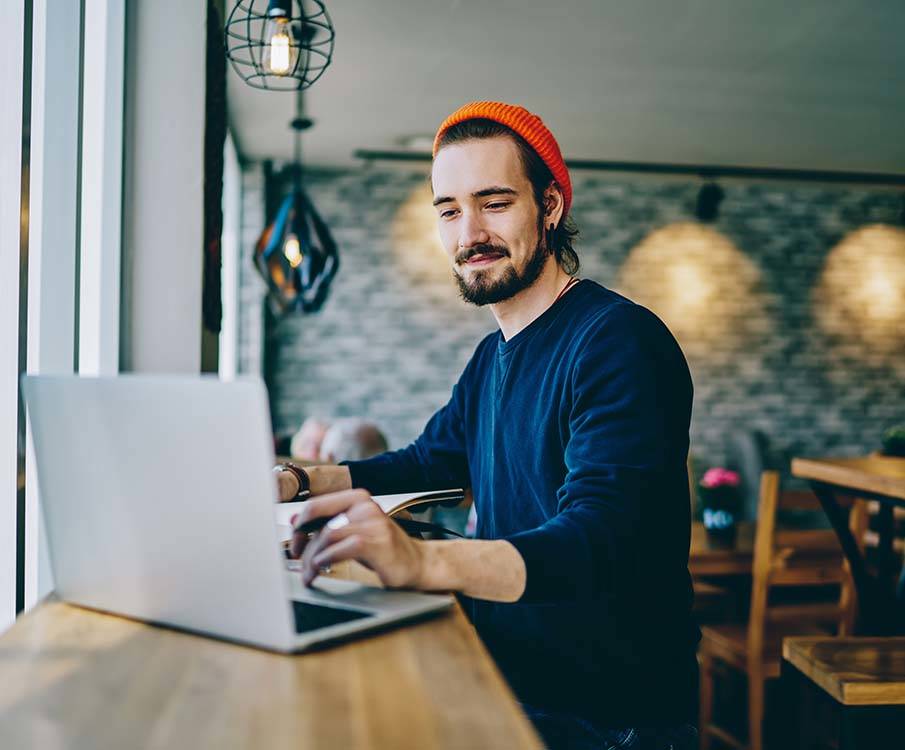 Mann som smiler og ser på datamaskinen